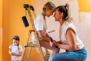 Mother and daughter they enjoy their time together while painting wall.