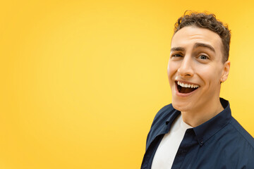 Closeup of funny young guy posing over yellow background