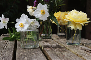 Reuse Glass Jam Jar for a vase of flower. Recycle Reuse Reduce concept. Jar Vase of enemies , rose, buddleia flower on old wooden table. 