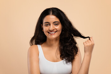 Happy young indian female showing her beautiful long hair after salon treatment