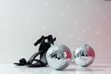 Fototapeta na wymiar Disco balls with women's shoes on a light background