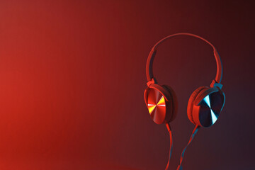 White, over-the-ear headphones with a wire on a colored, dark background.