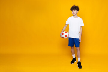 Young boy teenager soccer player on yellow background.