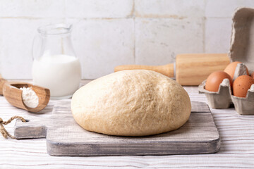 Making Basic Sweet Yeast Dough. Made with yeast, sugar, milk eggs, with mix of whole-wheat flour, butter, and salt. Ingredients on the kitchen table, light colors.