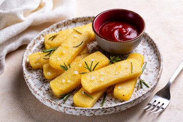 Fried polenta or polenta fries or chips with dipping tomato sauce, rosemarin, salt and garlic.  Italian cornmeal dish.