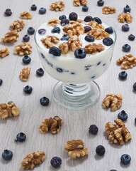 Blueberries, walnuts and yogurt on a wood table top