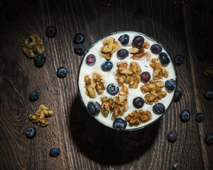 Blueberries, walnuts and yogurt on a wood table top