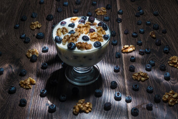 Blueberries, walnuts and yogurt on a wood table top