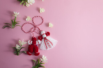 Martenitsa, Martisor among spring flowers on a pink background flat lay copy space - obrazy, fototapety, plakaty