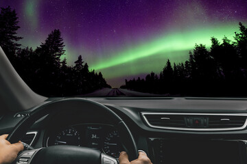 Man driving car and Northern lights (Aurora borealis) in the sky.