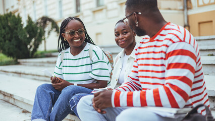 Group of three happy multiethnic friends talking outdoors. Portrait of young people of African American enjoying vacation together. Three african american friends outdoor. - obrazy, fototapety, plakaty