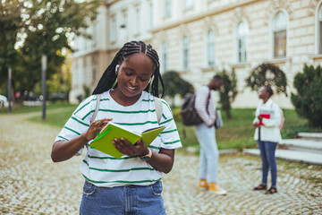 Shot of a young woman carrying her schoolbooks outside at college. Beautiful young woman with backpack and books outdoors. College student carrying lots of books in college campus.