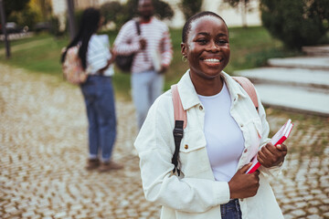 Cheerful African American Female Student With Smartphone And Workbooks Standing Outdoors, Happy Woman Walking In City After College Classes, Looking Away And Smiling, Copy Space - obrazy, fototapety, plakaty