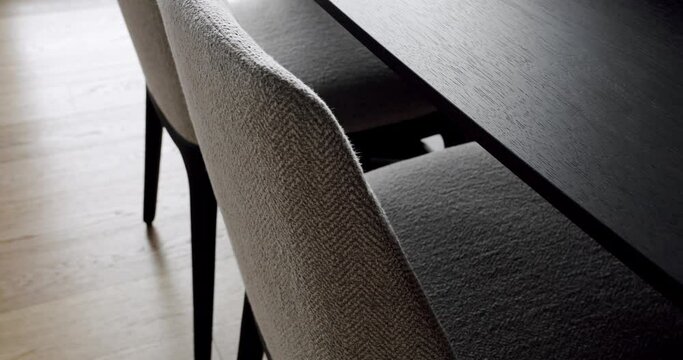 Closeup on modern chairs with upholstery and wooden dining table at luxury apartment. Contemporary furniture in dining room. Comfort seat in minimalist style