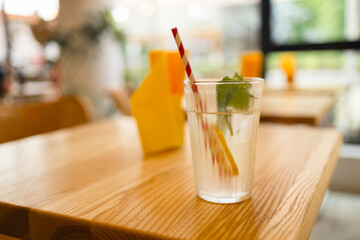 Glasses of lemon soda with ice and fresh mint on rustic wooden background. Glass of lemonade on wood table besides window