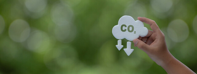 Hand holding Co2 simbol on Green background. Reduce CO2 emissions to limit climate change and...