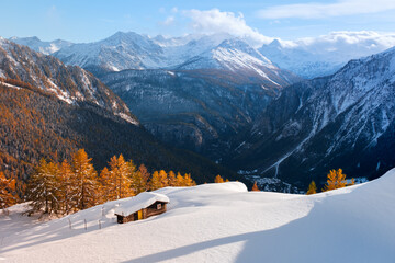 Small wooden cabin on snowy meadow on sunrise time. Courmayeur, northern Italy, Italian Alps. Snowy...