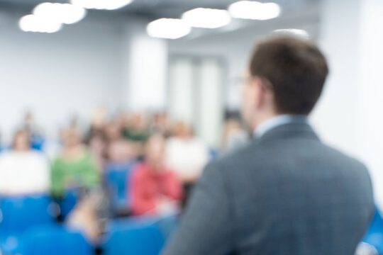 Male speaker at a conference, seminar, lecture. Personal growth training or business training. People's faces are not visible in the photo. Blurred. High quality photo