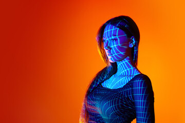 Portrait of beautiful young woman posing against orange studio background with neon reflection....