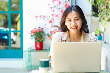 happy asian woman sitting in cafe working on laptop with smile wearing fashionable casual clothes,...