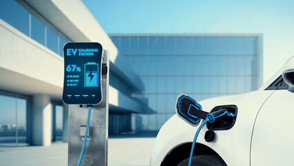 Innovative electric car connected to charging station with future architecture building background....