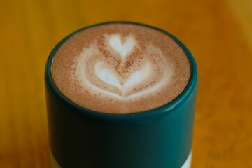 high angle view of a cup hot latte in green mug served on wooden table