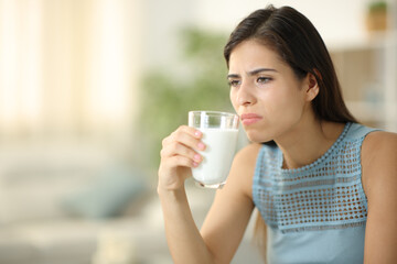 Disgusted woman smelling expired milk