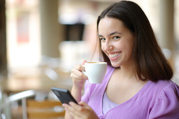 Female looking at camera holding phone and coffee