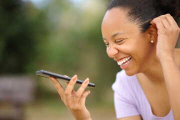 Happy black woman laughing dictating message on phone
