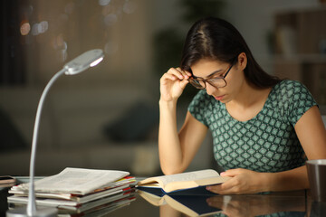 Woman with glasses reading a book in the night