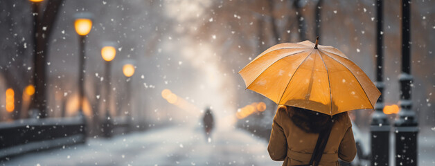 Cute girl walking on cold day in winter through a road with an umbrella and winter jacket in day...