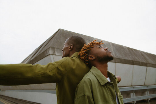 Two fashionable black men posing in urban area looking up