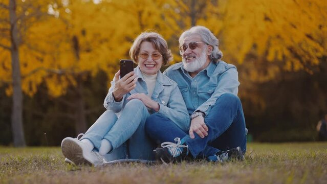 Mature people having online coversation in autumn park