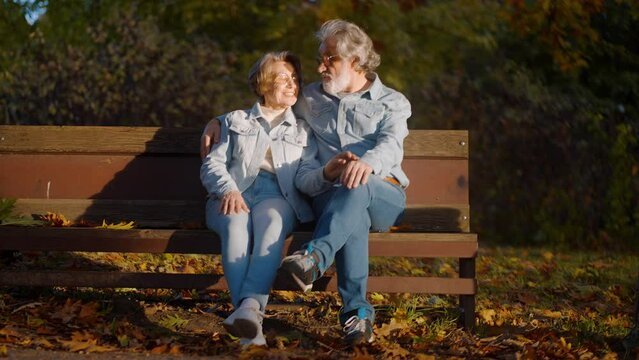 Senior couple cuddling to each other on wooden bench