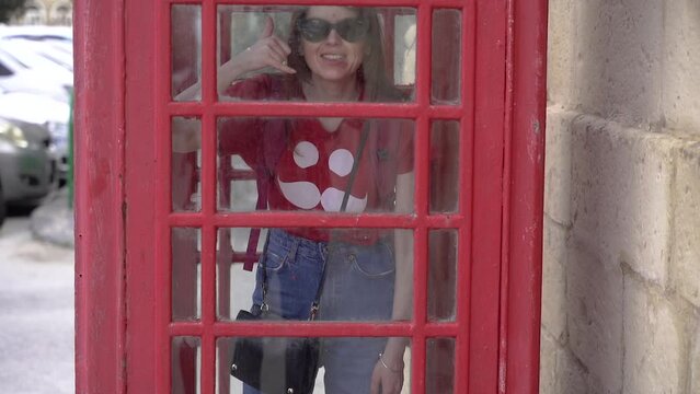 Classic red telephone booth. A girl inside a telephone booth.