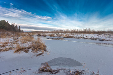 Frozen river and blue sky with clouds. Beautiful winter landscape.