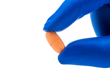 Hand with medical glove holding pill