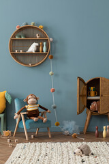 Cozy composition of kid room interior with round shelf, gray desk, green armchair, blue wall,...
