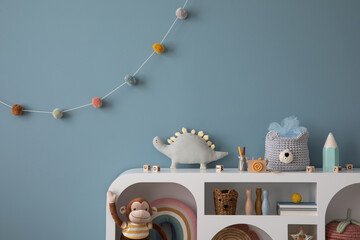Warm and cozy kid room interior with blue wall, modern white sideboard, plush lama, monkey, dog, toys, colorful garland on wall, pink basket, crayons and personal accessories. Home decor. Template.
