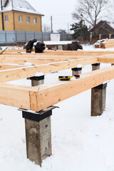 Corner of concrete pile foundation with floor board from square-sawn timber, several builders...