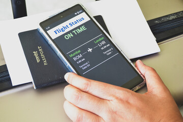 Indian traveller checking Flight status using tracker app on her smartphone. Selective focus.