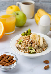Oatmeal with fruits and nuts, orange juice, egg in a stand, traditional, healthy breakfast. Proper nutrition, diet..