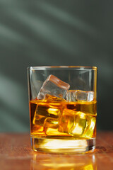 A glass of whiskey and ice old polished table on dark background