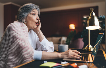 Amazed woman working on laptop in living room