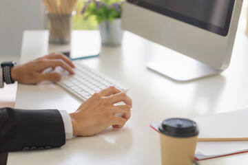 Close-up of male hand clicking wireless digital mouse working with desktop computer at office desk