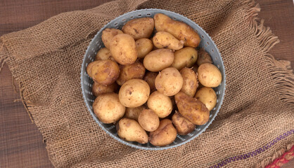 Fresh small potatoes for cooking in a wooden bowl. With copy space on white background.