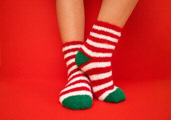 Female feet in fluffy New Year or Christmas warm socks. The colors of the socks