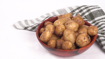 Fresh small potatoes for cooking in a wooden bowl. With copy space on white background.