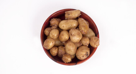 Fresh small potatoes for cooking in a wooden bowl. With copy space on white background.