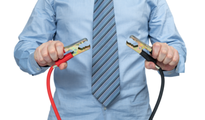 A man in a shirt and tie holds two cables with battery clips in his hands, without a face, isolated on a transparent background png